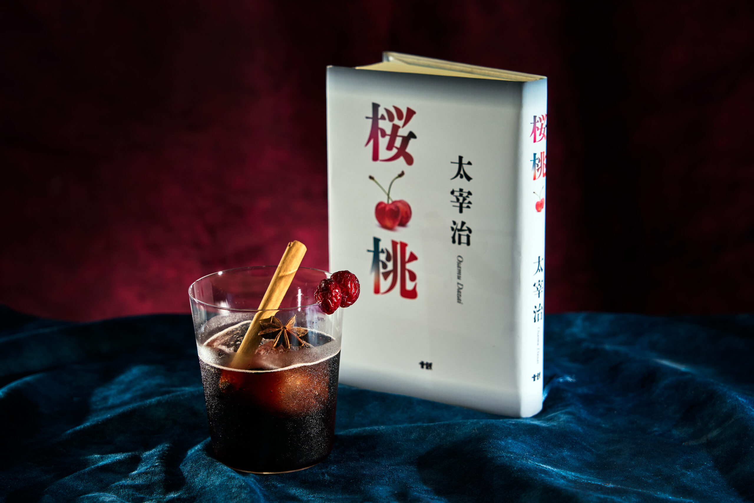 太宰治『桜桃』の白い本を背に、シナモンと八角、ドライチェリーを飾った漆黒のスパイシーチェリーコーク